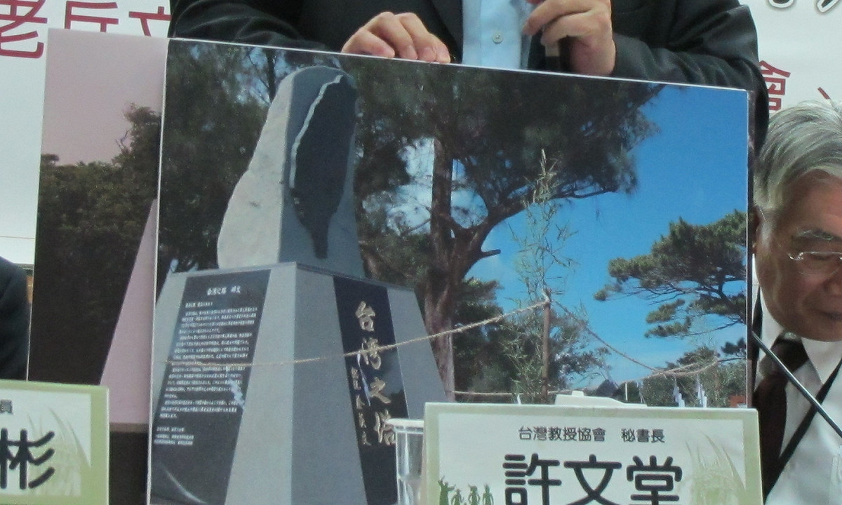 台灣教授協會、日本沖繩翼友會與高雄市關懷台籍老兵文化協會今年9月29日在台北舉行「勿忘台灣空戰烈士」記者會，台教會秘書長許文堂手拿「台灣之塔」塔體落成活動照片，左下方刻有「總統蔡英文」。 圖：新頭殼資料照片