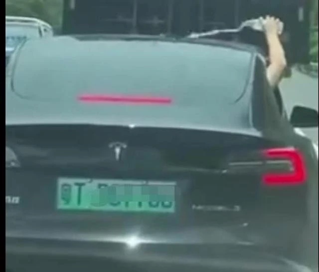 中國特斯拉車主「手動」替車子降溫，把礦泉水澆至車頂。 圖：擷取自第一財經