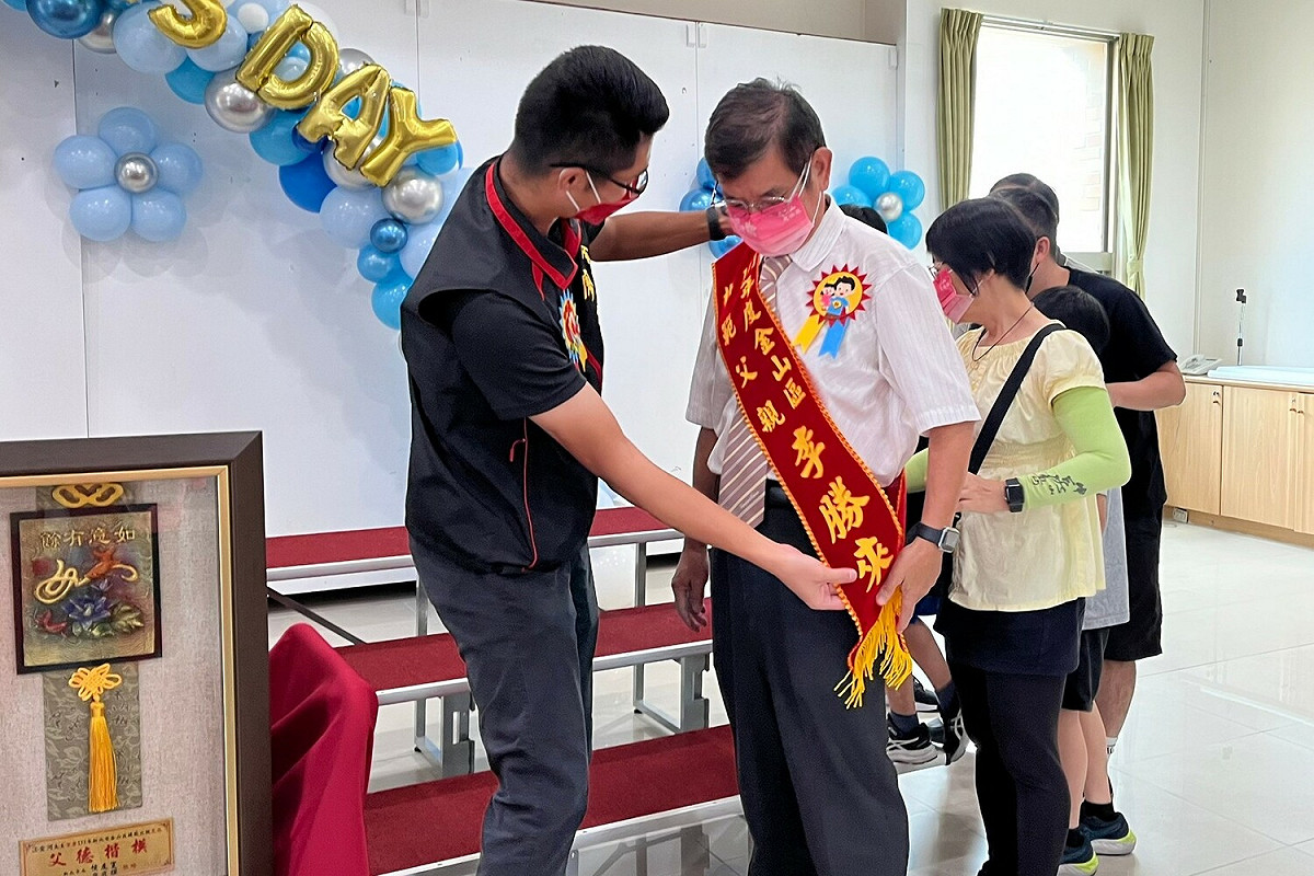 金山區長廖武輝為爸爸們掛背帶獻上祝福。 圖：金山區公所提供