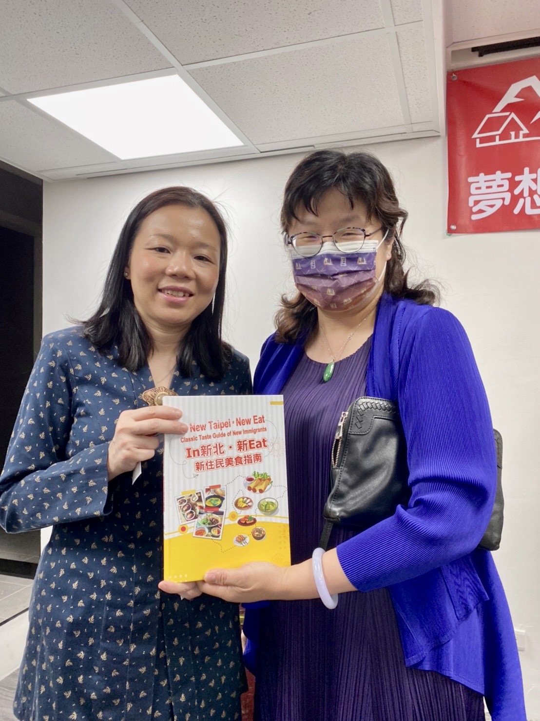 經發局長何怡明（左）與馬來西亞友誼及貿易中心代表何瑞萍合影，攜手推廣新住民美食手冊，促進國際美食交流與火花。 圖：新北市經發局提供