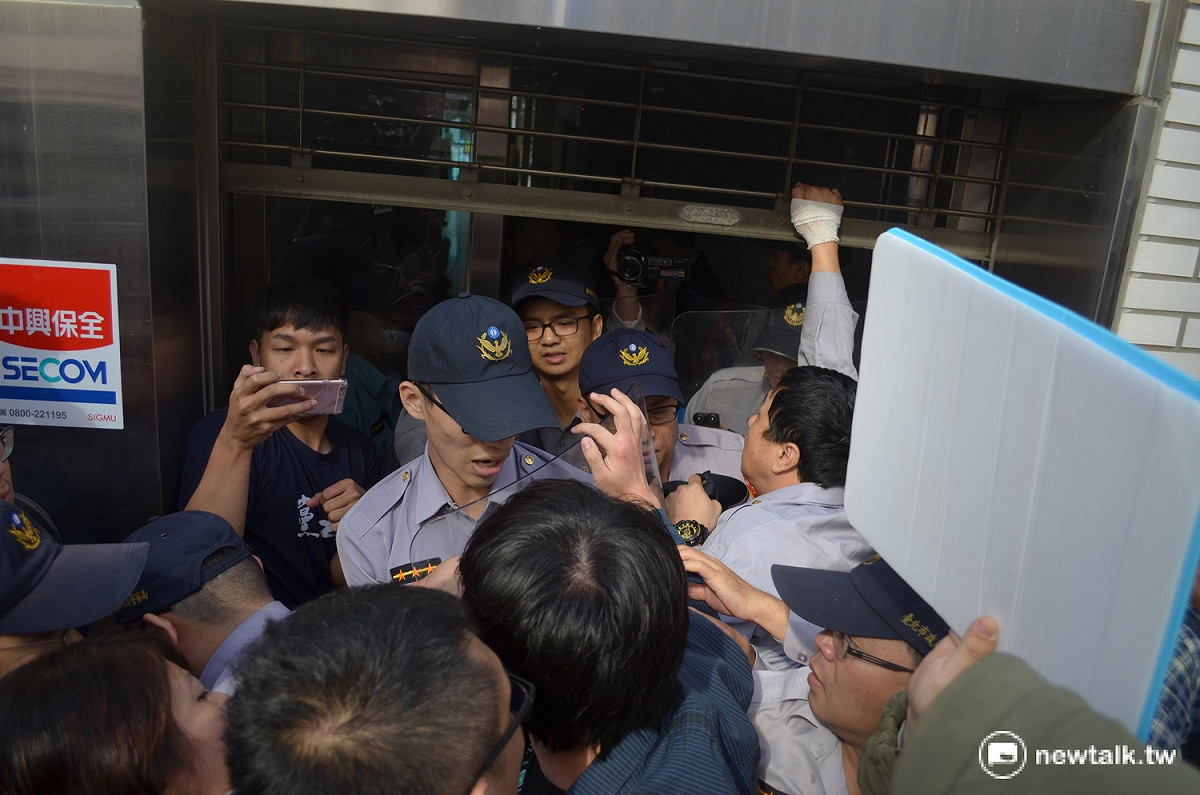 國民黨青年團一度翻越圍牆，企圖闖入黨產會大樓後門，遭警方擋下。 圖：柯昱安/攝
