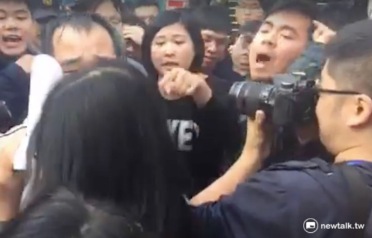 國發會法協女員工（左下，拿白紙遮臉者）遭到國民黨青年團誤認為黨產會員工，群起辱罵她「不要臉」。 圖：翻攝自新頭殼直播畫面