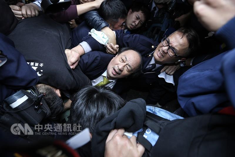 民進黨立法院黨團總召柯建銘（中）2日在返回辦公室途中，遭到立法院週邊抗議勞基法修法的勞團包圍，發生衝突，並被推倒在地。  圖：中央社