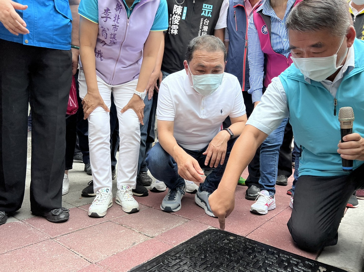 養工處長馮兆麟向侯友宜說明，為提供行人友善通行環境，特別貼心的在人行道上的人孔蓋鋪設一個保護裝置，讓人孔蓋與人行道鋪磚更密合，以保障行人通行安全。 圖：新北市工務局提供