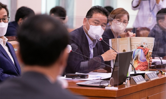 國會中，韓國共同民主黨議員林鐘成手持雜誌，展示引發爭議的相關照片，並向文化遺產廳廳長崔應天提出質疑。 圖:翻攝自環球網