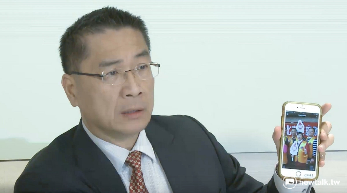 行政院發言人徐國勇拿出過去曾率團捐血的照片，強調不會因為血液基金會內部董事具有黨政色彩，就不參與捐血活動。 圖：柯昱安/攝