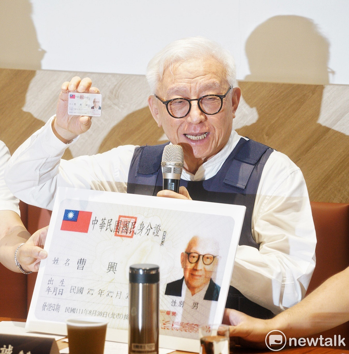 曹興誠穿著防彈衣，並秀出新身分證。 圖：張良一／攝
