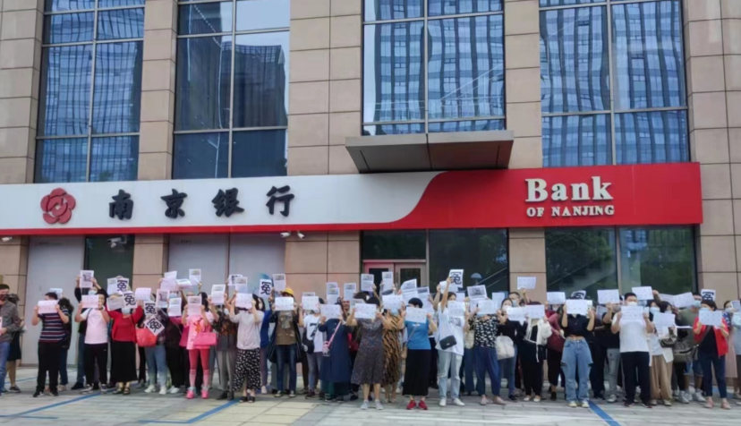 儲戶在銀行外高舉「冤」字牌抗議。 圖: 翻攝自 用戶7738534297 微博