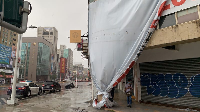 颱風軒嵐諾影響，高雄市警方3日上午在三民區巡邏時，發現建國三路與中山一路口有廣告帆布遭強風吹毀，影響交通，立即將帆布收齊、在牆角綁緊，並聯繫不動產等單位前來處理。 圖：中央社記者曾以寧傳真 111年9月3日（民眾提供）