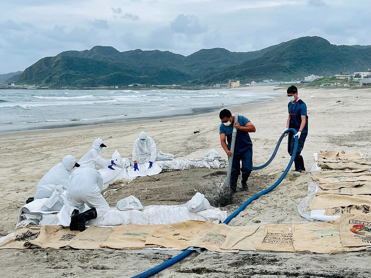 應變人員進行「岸際污染砂石清除油污洗滌工法」。 圖：新北市環保局提供