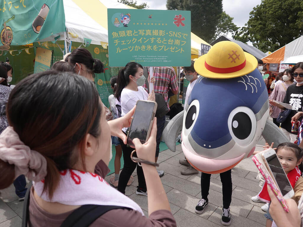中華文化總會主辦2022 TAIWAN PLUS台灣吉日生活節17日在東京登場，台南設攤推出結合飲食、文化與觀光元素的趣味性集客活動，民眾爭相與吉祥物魚頭君拍照。 圖/中央社