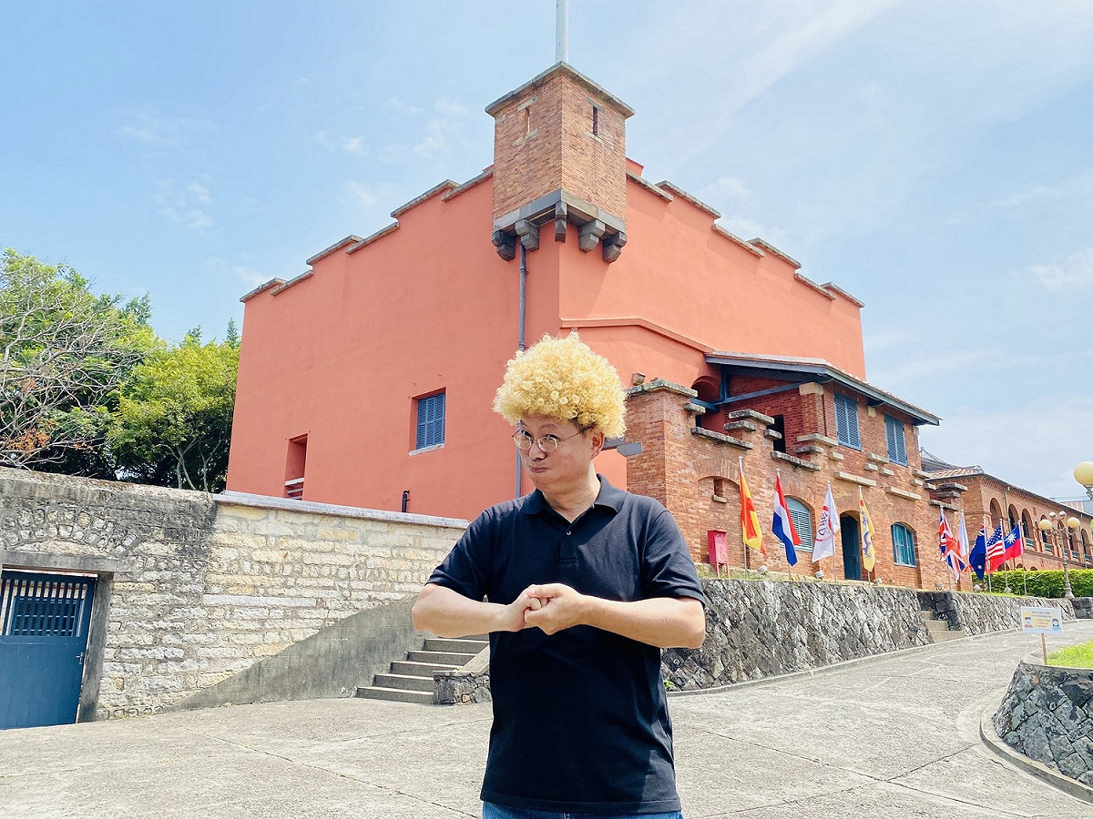 淡水古蹟博物館邀請神級手譯員李振輝合作台灣手語導覽影片，他特別戴假髮介紹淡水紅毛城，展現專業又俏皮的一面。 圖：淡水古蹟博物館/提供