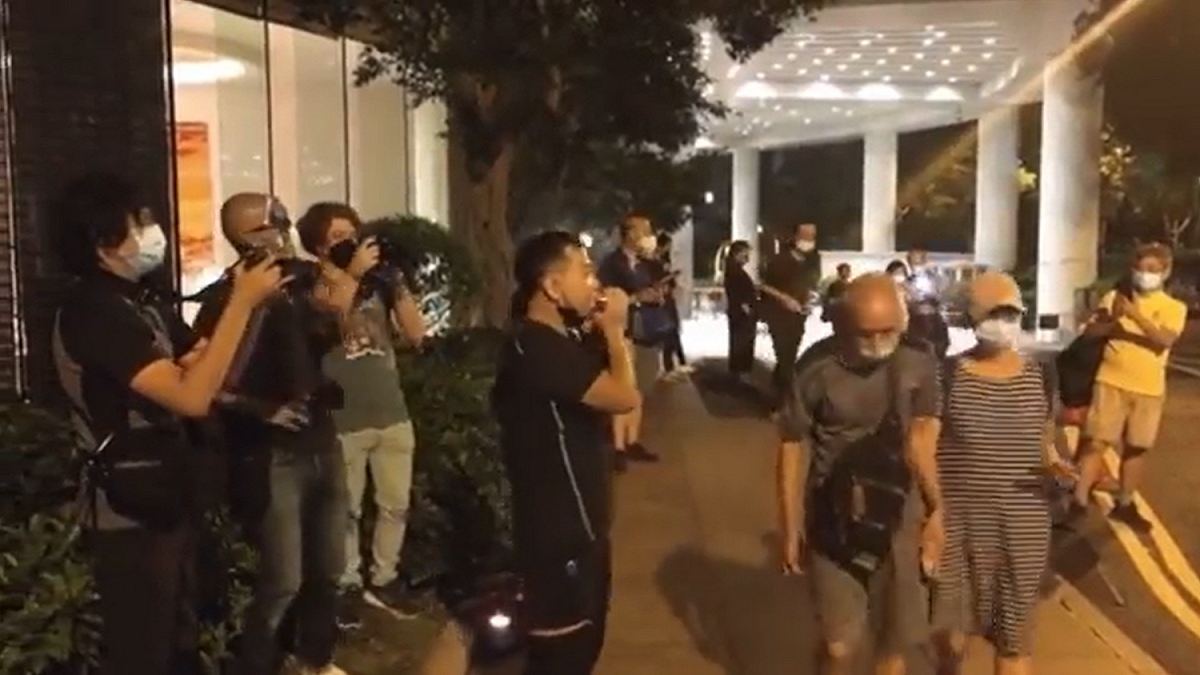 男子在英國駐香港領事館外用口琴吹奏《 願榮光歸香港 》。  圖: 擷取自 Fight For Freedom. Stand With Hong Kong. 重光團隊推特