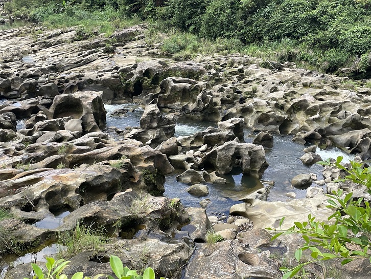 基隆河床岩石上有許多大大小小圓滑的坑洞就是世界級地理景觀「壺穴」。 圖：新北市觀旅局提供