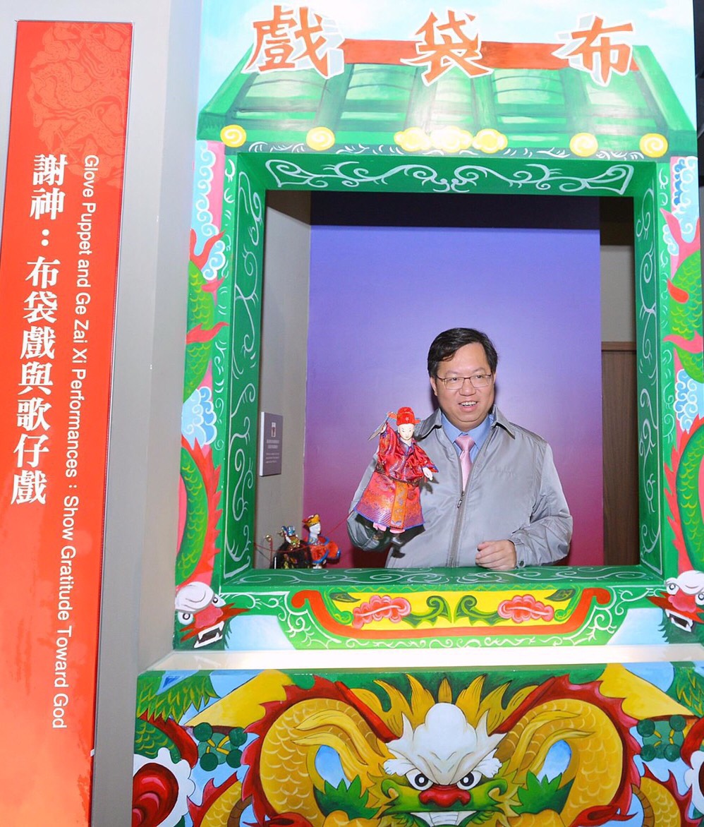 桃園土地公文化館內，為呈現傳統廟會文化特色，還特地設置了歌仔戲台和布袋戲棚，當然也有傳統布袋戲的布偶，桃園市長鄭文燦，每次視察時，都不忘拿起布偶，把玩一下，重溫回味童年的滋味。 圖：翻攝自桃園市文化基金會官網