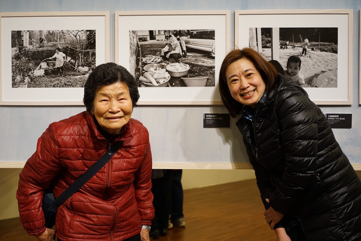旅程.印象台三線攝影展的策展人劉慧貞（右1）與背後照片的影中人本尊彭金妹，今年已高齢85歲的彭金妹，看著年輕時整理山城特產桂竹筍的影像，笑的闔不攏嘴。 圖：台灣水/黃裕順提供