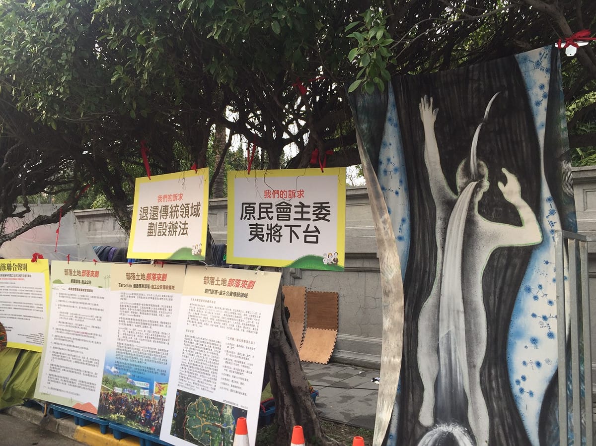 蘭嶼逹悟族著出草服裝背心，席地而坐，他們 主張：核廢遷出蘭嶼，要求原住民委員會主委夷將下台、退還傳統領域劃設辦法。現場的抗議及訴求標語旁，還出現抽象的帆布海報，平添幾分藝術氣息 圖:羅碧霞/攝