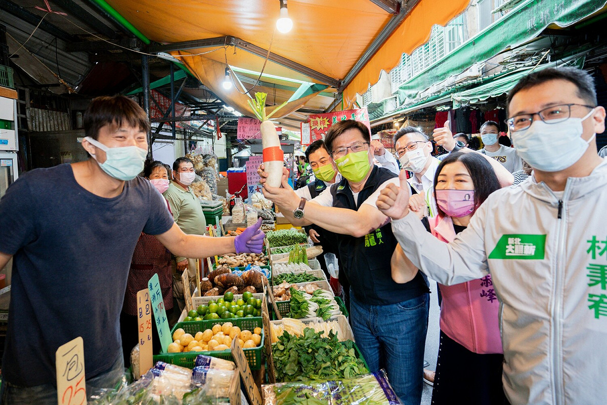 林佳龍到新莊宏泰市場掃街拜票，攤商送蘿蔔祝福。 圖：林佳龍競辦提供