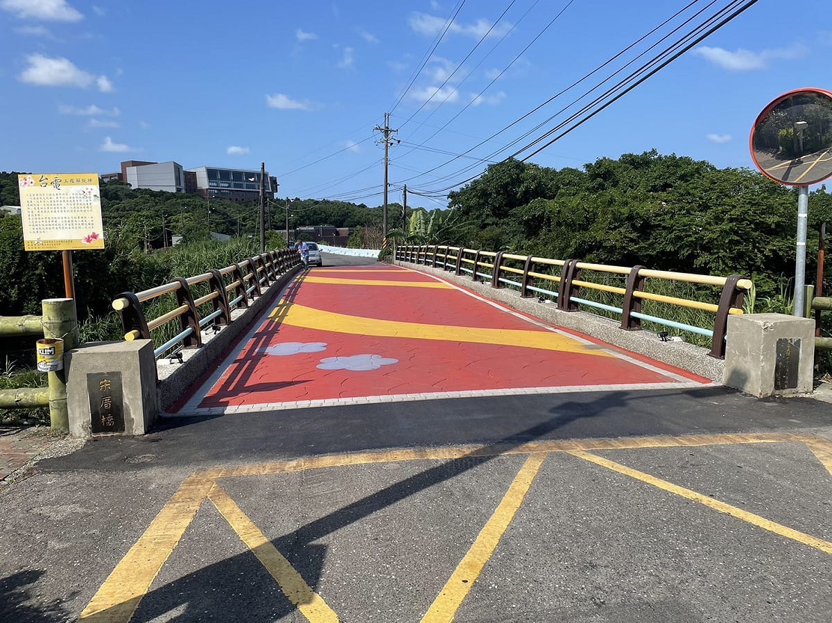 改善後的三芝宋厝橋，橋梁欄杆以不同顏色油漆搭配，增加活潑度；橋面則採用壓印彩色圖樣的瀝青鋪面，平坦又美觀，並設置投射照明燈具，維護原先豐富生態，提升道路安全。 圖：新北市工務局提供