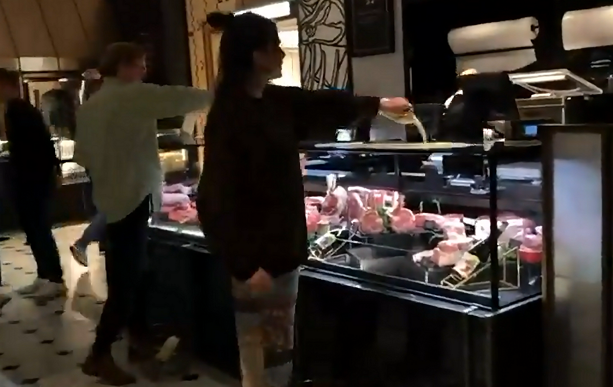 環團人士將牛奶倒在肉品展示櫃上，宣傳反肉食。 圖: 翻攝自動物顛覆推特
