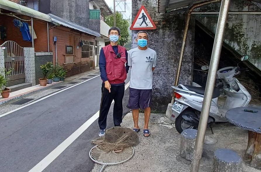 在陳情人黃先生（右）協助下，獸醫王嚴緒（左）順利使用捕犬網捕捉到午睡中的病犬，犬隻似乎無反抗力。  圖：新北市動保處提供
