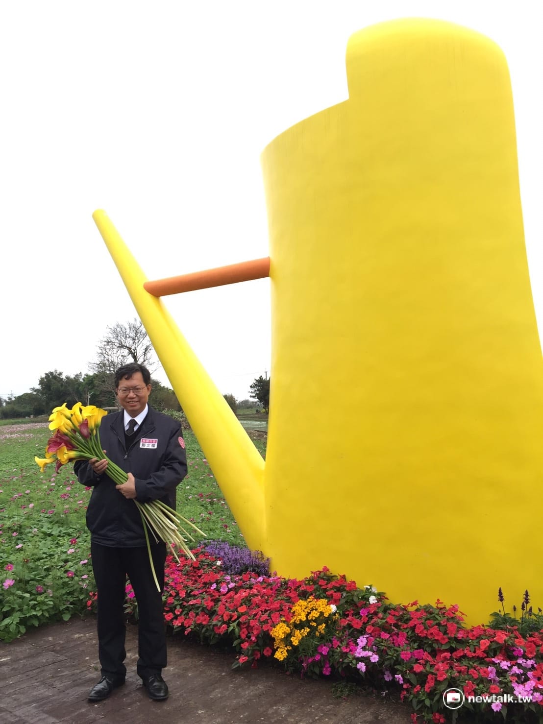桃園市長鄭文燦在桃園彩色海芋季「地景藝術花海區」，抱著新鮮艷黃海芋，樂得與花海中的4米高的香蕉黃澆水壼合影，並力推即將於3月31日開幕的2017桃園市彩色海芋季。 圖:羅碧霞 攝