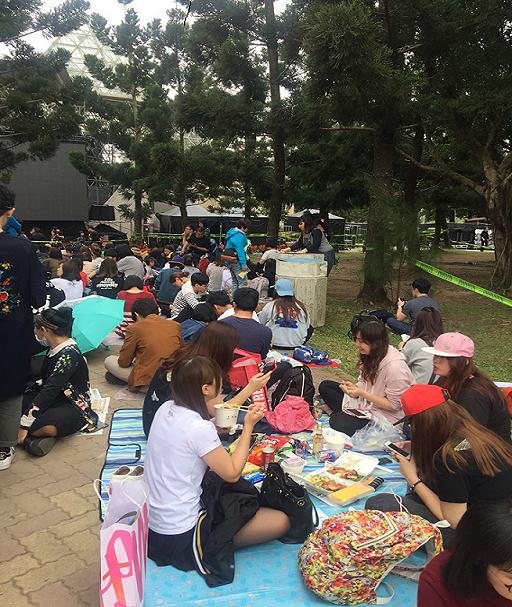 大安森林公園29日下午已湧入大量人潮，不少粉絲席地而坐，吃東西打發時間，也有人看書消磨時間。 圖：郭芳嘉／攝
