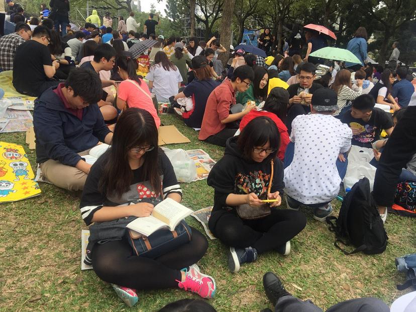 不少粉絲席地而坐，吃東西打發時間，也有人看書消磨時間。 圖：郭芳嘉／攝