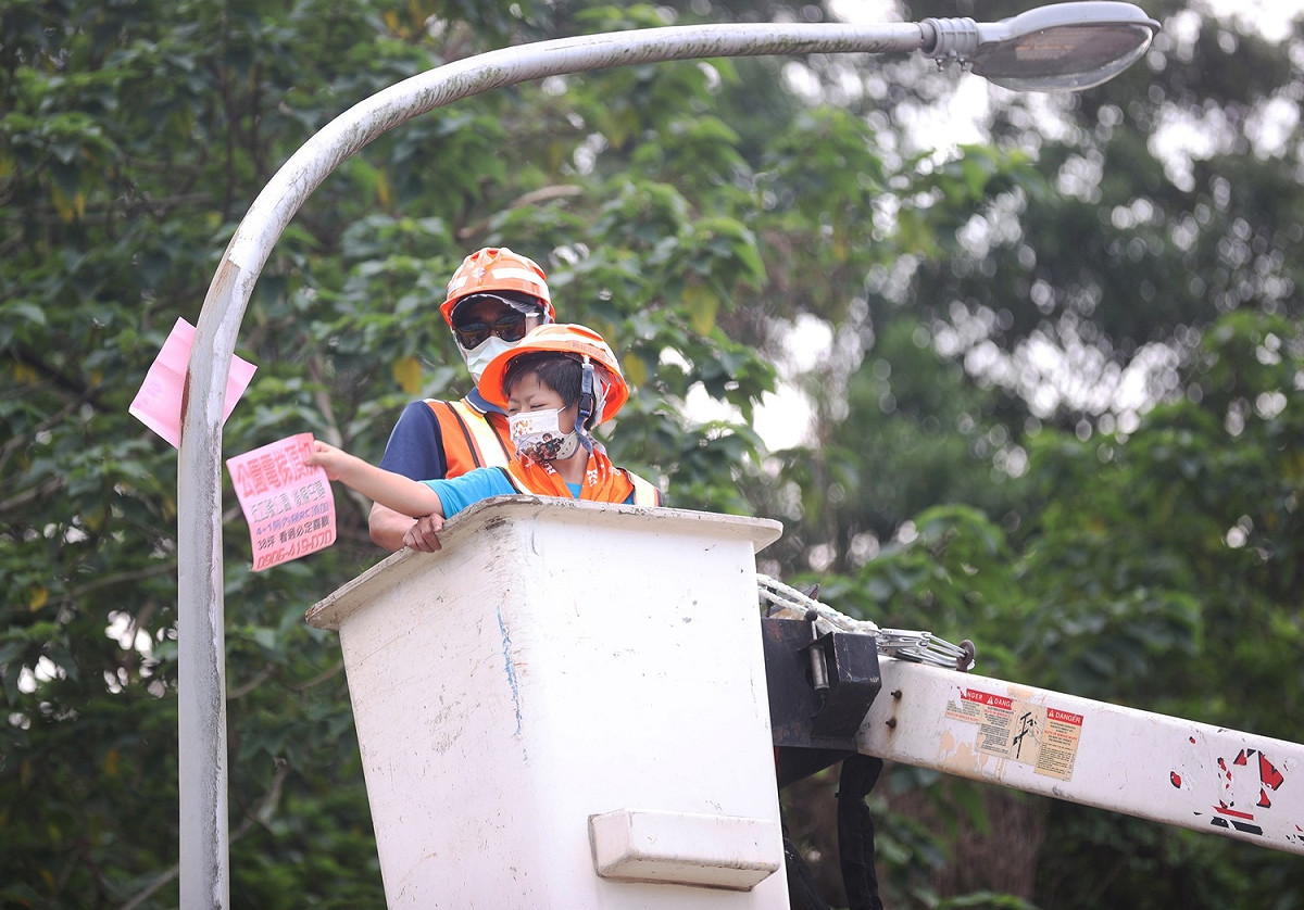 小局長搭上高空作業車體驗撕除高空小廣告。 圖：新北市環保局提供