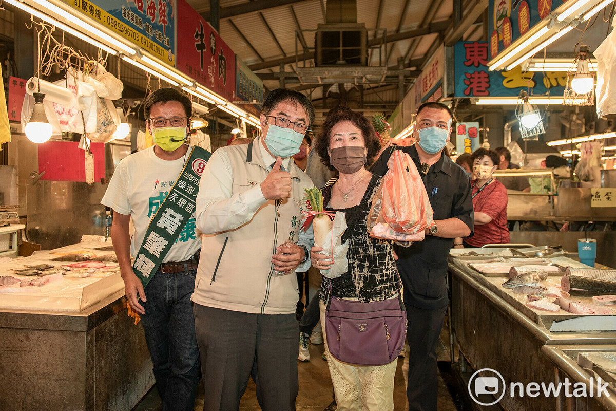黃偉哲帶著民進黨市議員候選人朱正軒與黃肇輝，至黃昏市場掃街拜票，受到民眾熱烈歡迎，攤商與民眾不只搶著要和市長合影，更有攤販熱情地送上象徵「包中」的包子與粽子，以及象徵「好彩頭」、「旺來」的蘿葡和鳳梨，預祝黃偉哲高票當選。 圖：黃博郎／攝