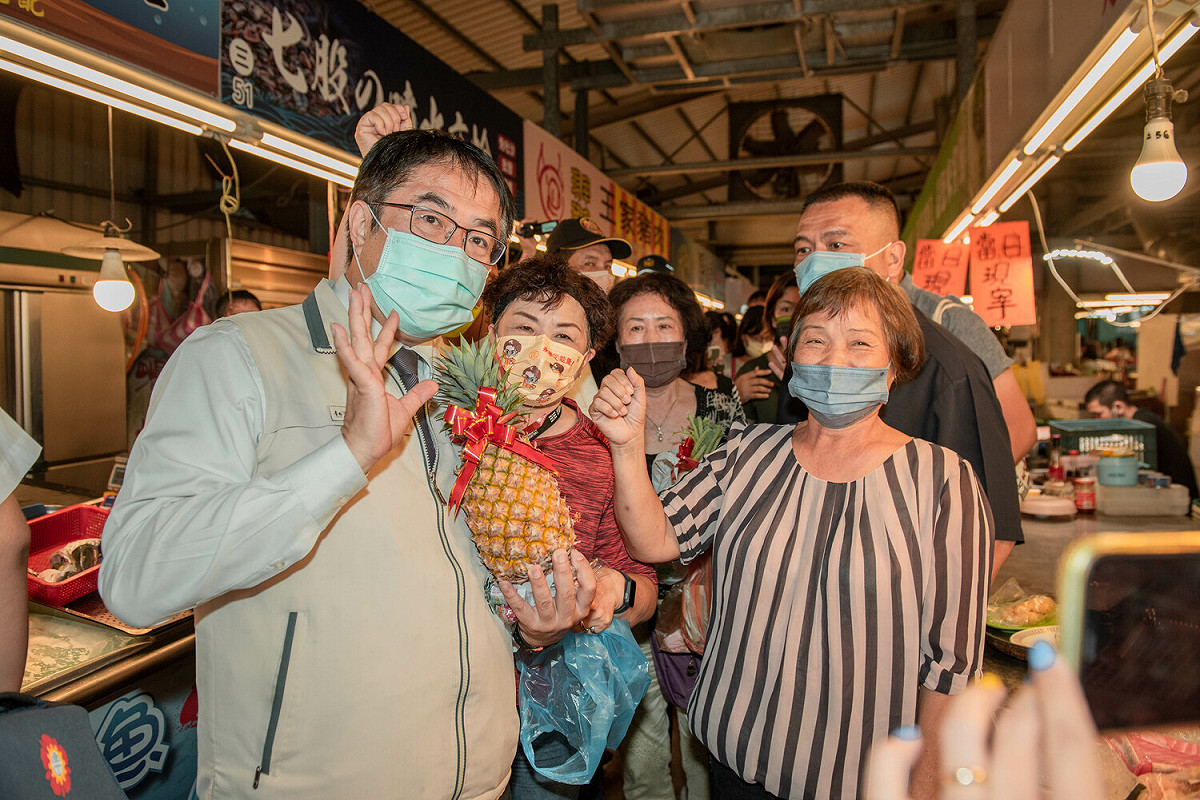 黃偉哲帶著民進黨市議員候選人朱正軒與黃肇輝，至黃昏市場掃街拜票，受到民眾熱烈歡迎，攤商與民眾不只搶著要和市長合影，更有攤販熱情地送上象徵「包中」的包子與粽子，以及象徵「好彩頭」、「旺來」的蘿葡和鳳梨，預祝黃偉哲高票當選。 圖：黃博郎／攝