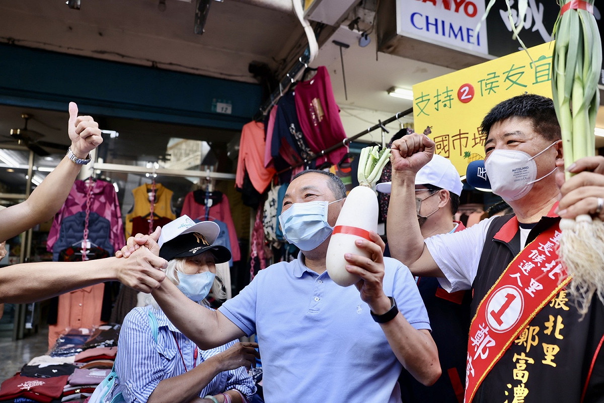 侯友宜由新店區張北里長鄭富濃（右一）等陪同掃惠國市場，不少攤販爭相熱情拍照。 圖：侯友宜競選公室提供