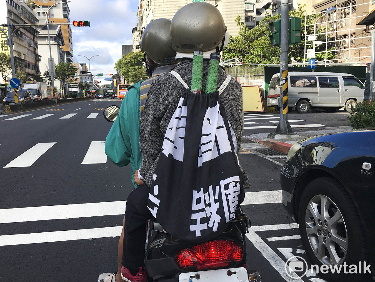 一位民眾將黑色的競選旗幟改做成球拍袋。 圖：張良一/攝