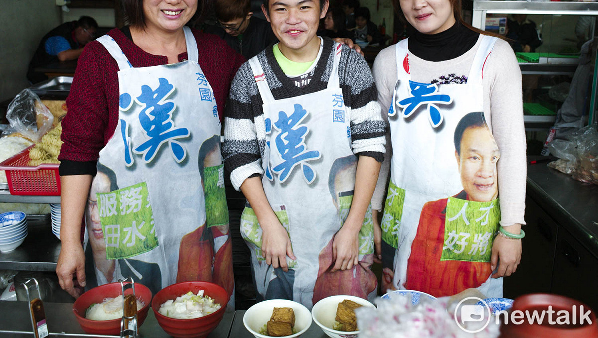 埔里一家麵店的老闆娘發揮巧思將候選人的競選旗幟變成圍裙。 圖：張良一/攝