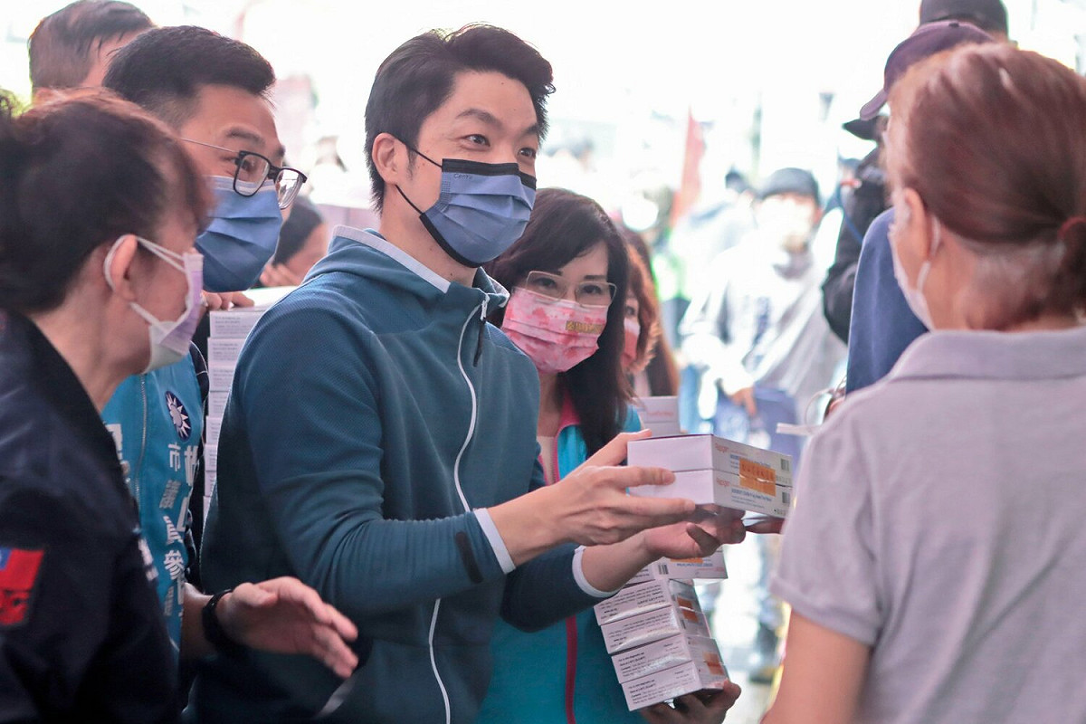 國民黨台北市長當選人蔣萬安（中）今年5月在松山區霞海城隍廟發放快篩劑，他可能不知道鄰近的內湖區清白里長，涉及以中資快篩劑賄選。 圖：翻攝自蔣萬安臉書