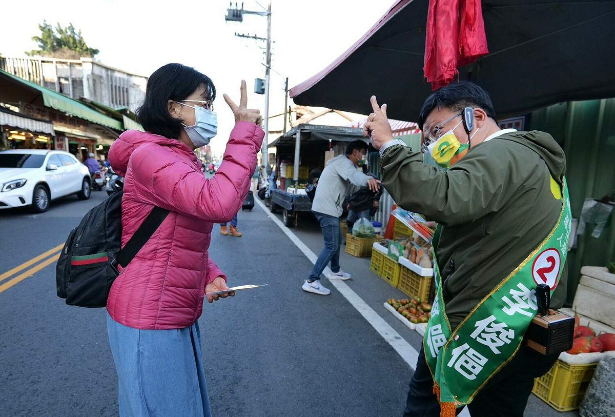 登記2號的李俊俋市場拜票時，與民眾比出2的手勢。 圖：李俊俋競選總部/提供