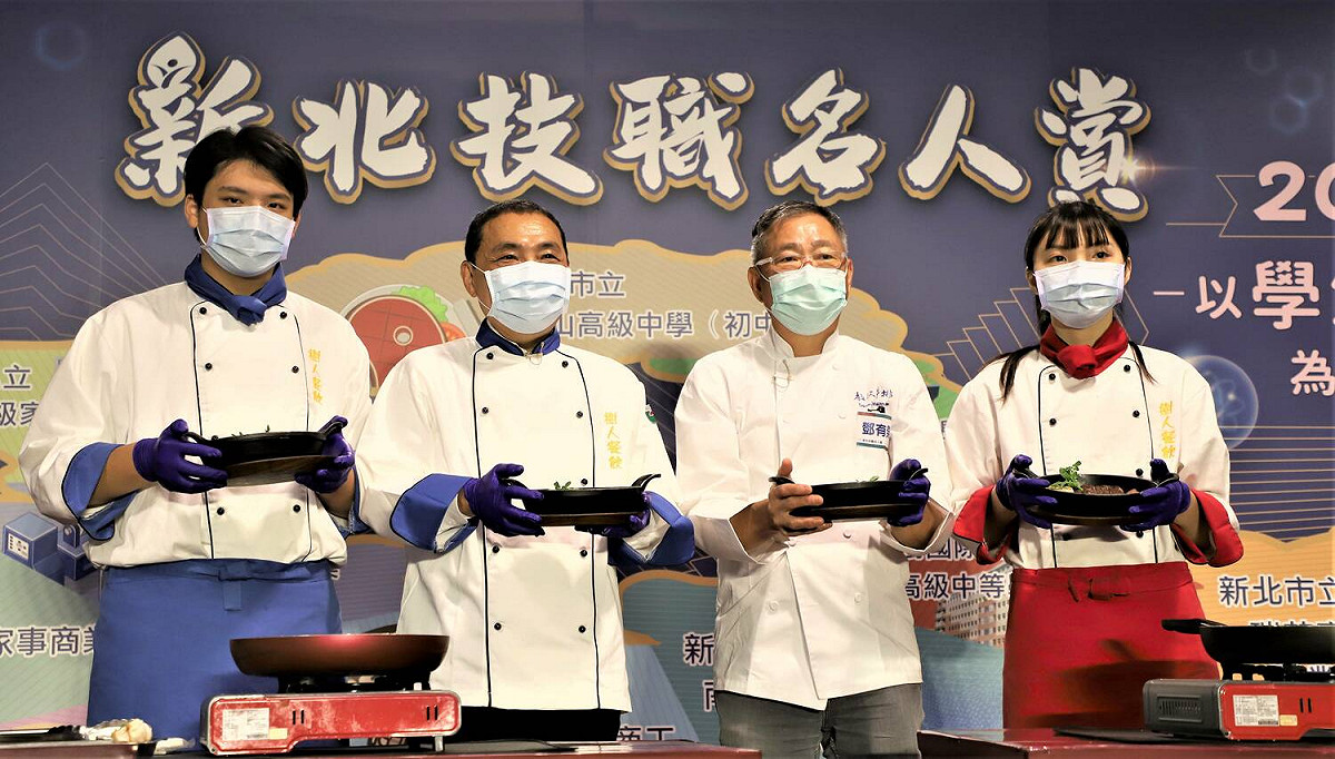 侯友宜（左2）、牛排教父鄧有癸（右2）與餐飲科學生紀甫陞（左1）、謝旻芸（右1）一起煎牛排。 圖：新北市教育局提供