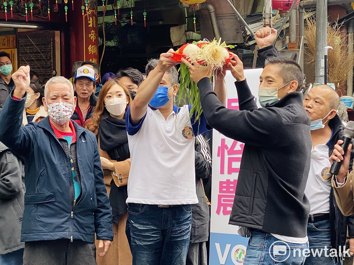 民進黨立委參選人吳怡農接受廟方贈送蘿蔔象徵「好彩頭」、蒜象徵「凍蒜」。 圖：周煊惠 / 攝