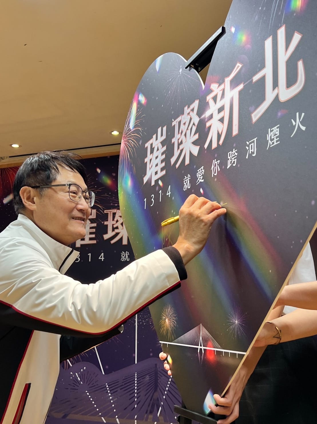 陳純敬在愛心造型板簽名，為今年跨河煙火揭幕。 圖：新北市高灘處提供