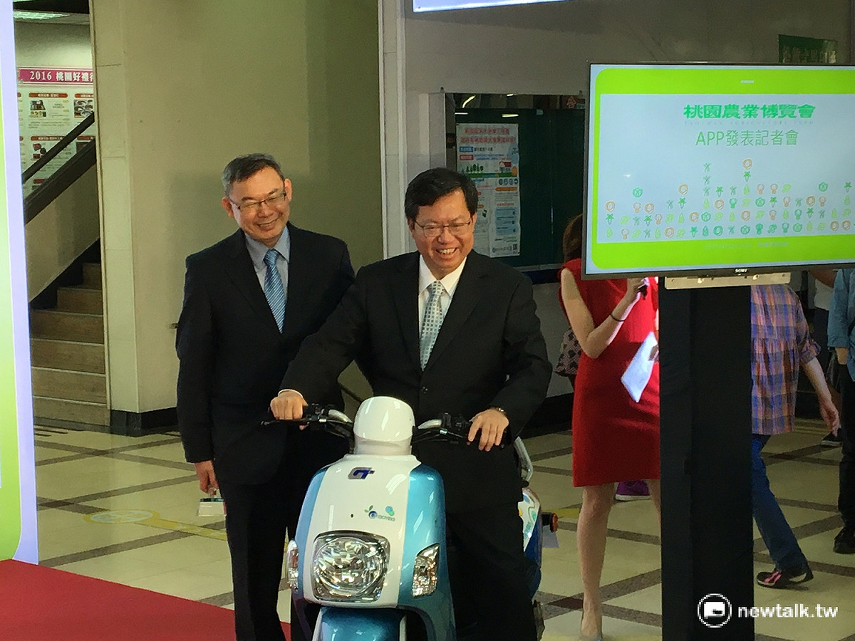 桃園市長鄭文燦（右）與中華汽車代表作勢騎乘E-Moving。 圖:鍾孟軒/攝