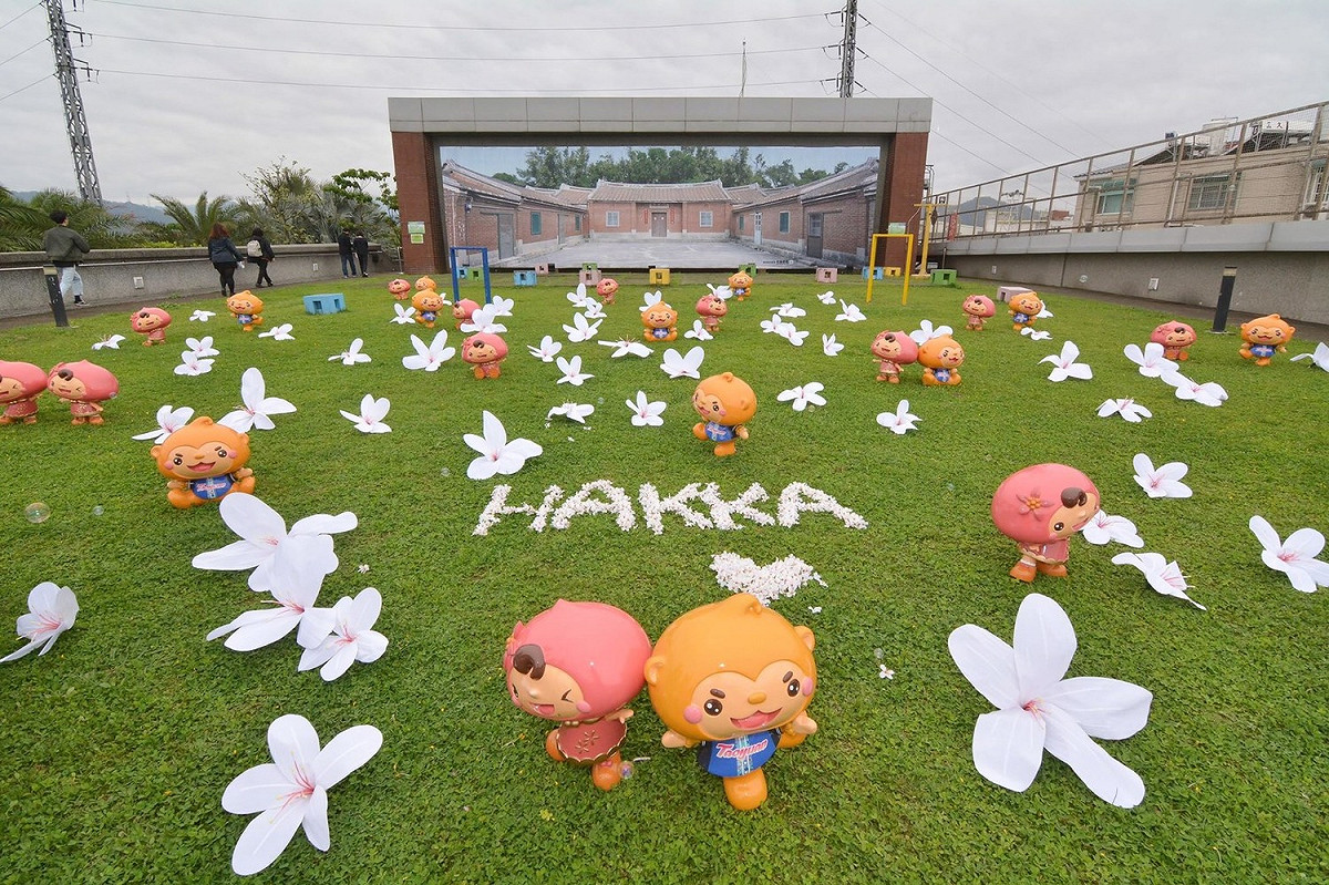 今年的桐花地景藝術作品「桐花公仔大進擊」，結合桃園市客家文化館的綠地，以大小錯落的手作布桐花為主體。 圖：桃園市政府提供