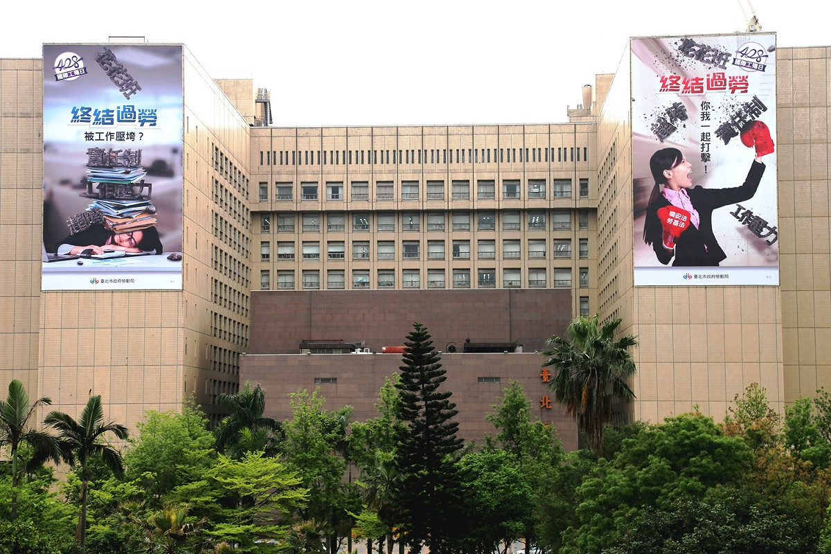 勞動局在台北市政府外牆掛上巨幅廣告，宣誓「終結過勞，拳力出擊」。 圖：台北市政府提供。
