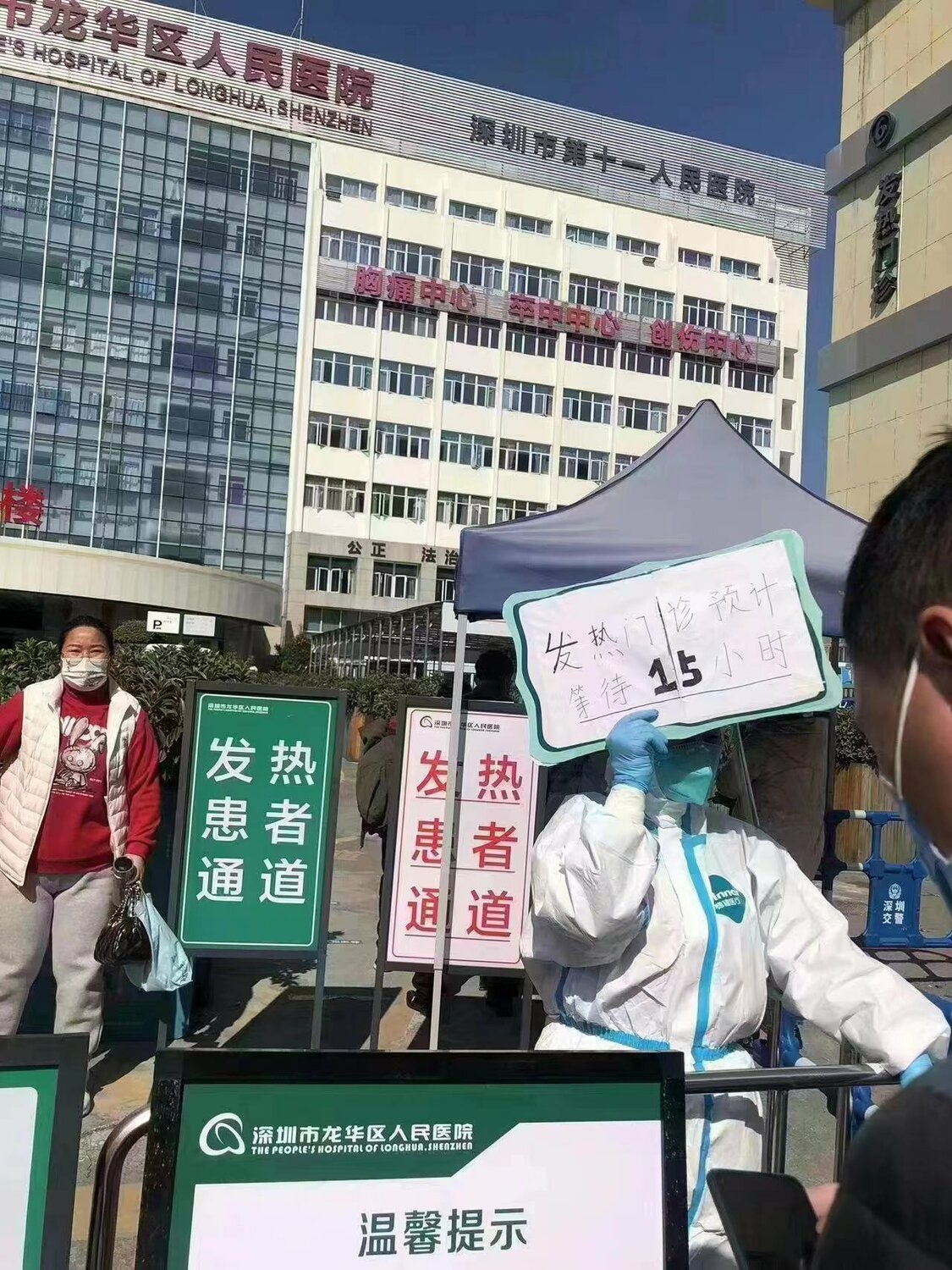 中國深圳龍華區人民醫院， 疫情時工作人員舉出手牌，寫明「發熱門診預計等待 15 小時」。 圖：翻攝自方舟子推特