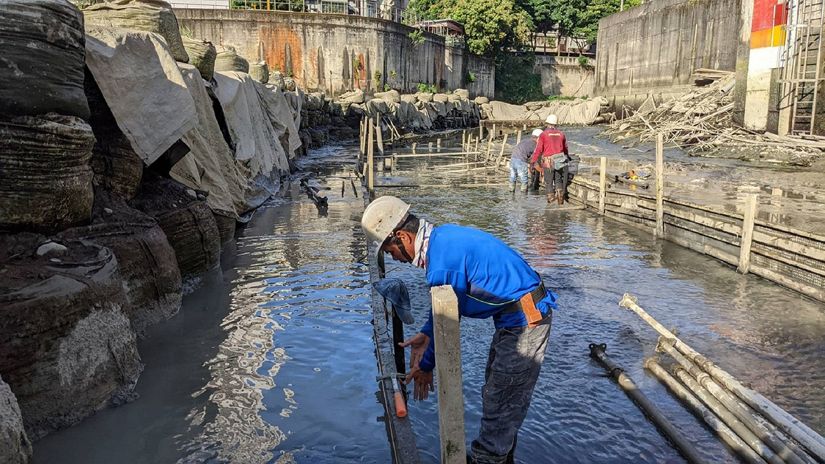 施工人員在水位受潮汐、砂湧影響及惡劣環境中進行渠道子溝施工。 圖：新北市水利局提供