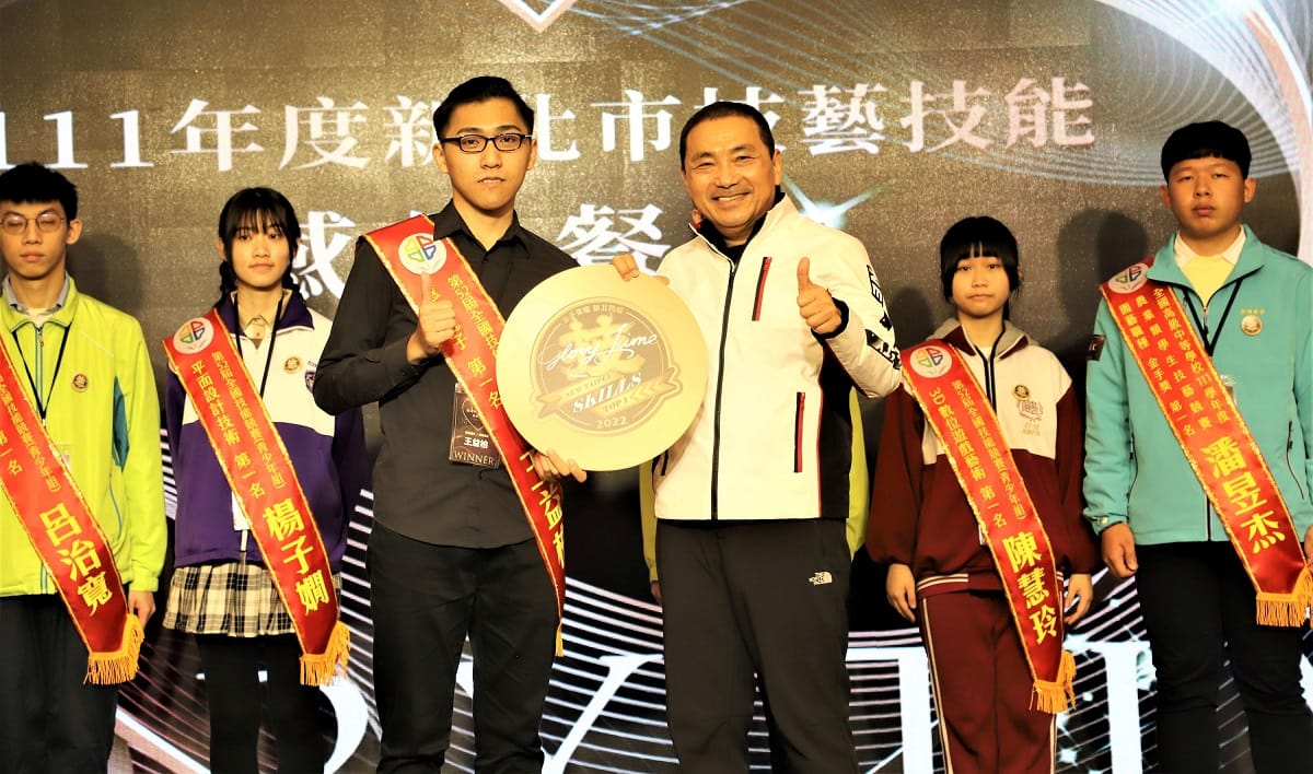 侯友宜（右）贈送每位獲獎師生一枚獨家-2022年新北金手榮譽徽章。 圖：新北市教育局提供