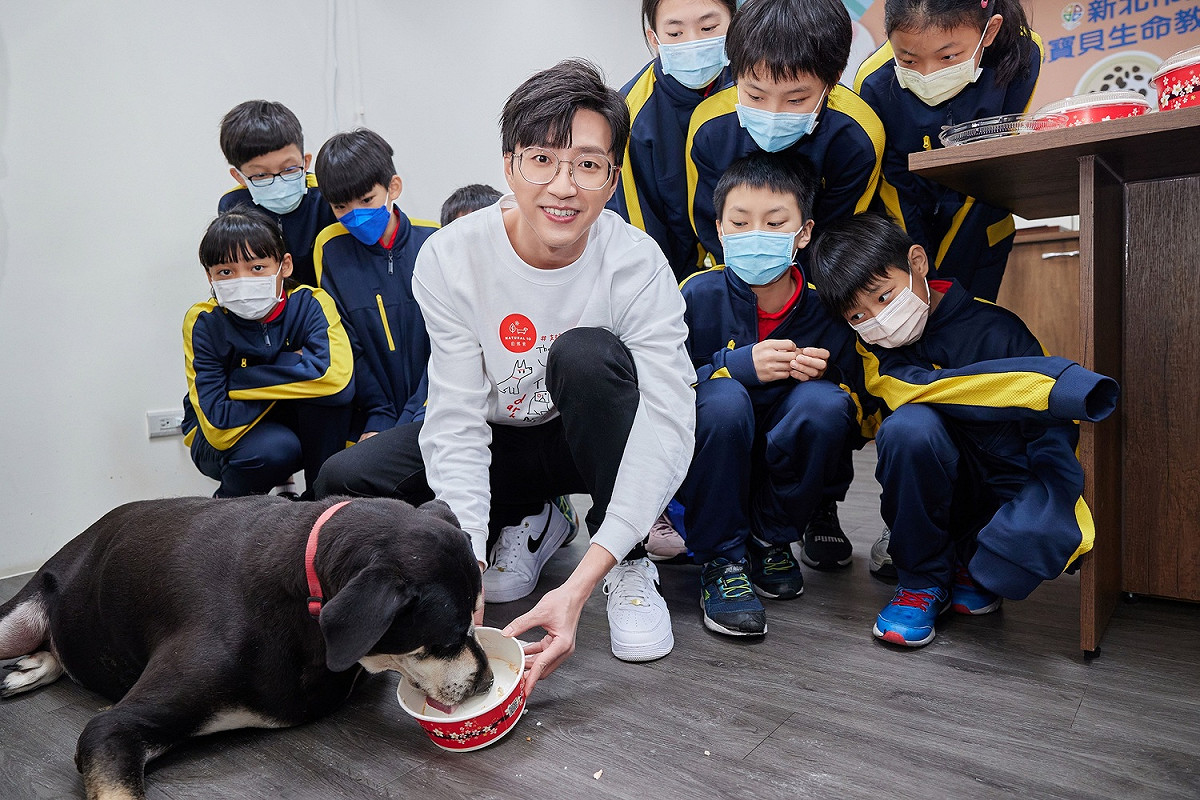 生命教育園區招牌大頭開心吃著江宏傑手作的幸福大吉米糕。 圖：新北市動保處提供