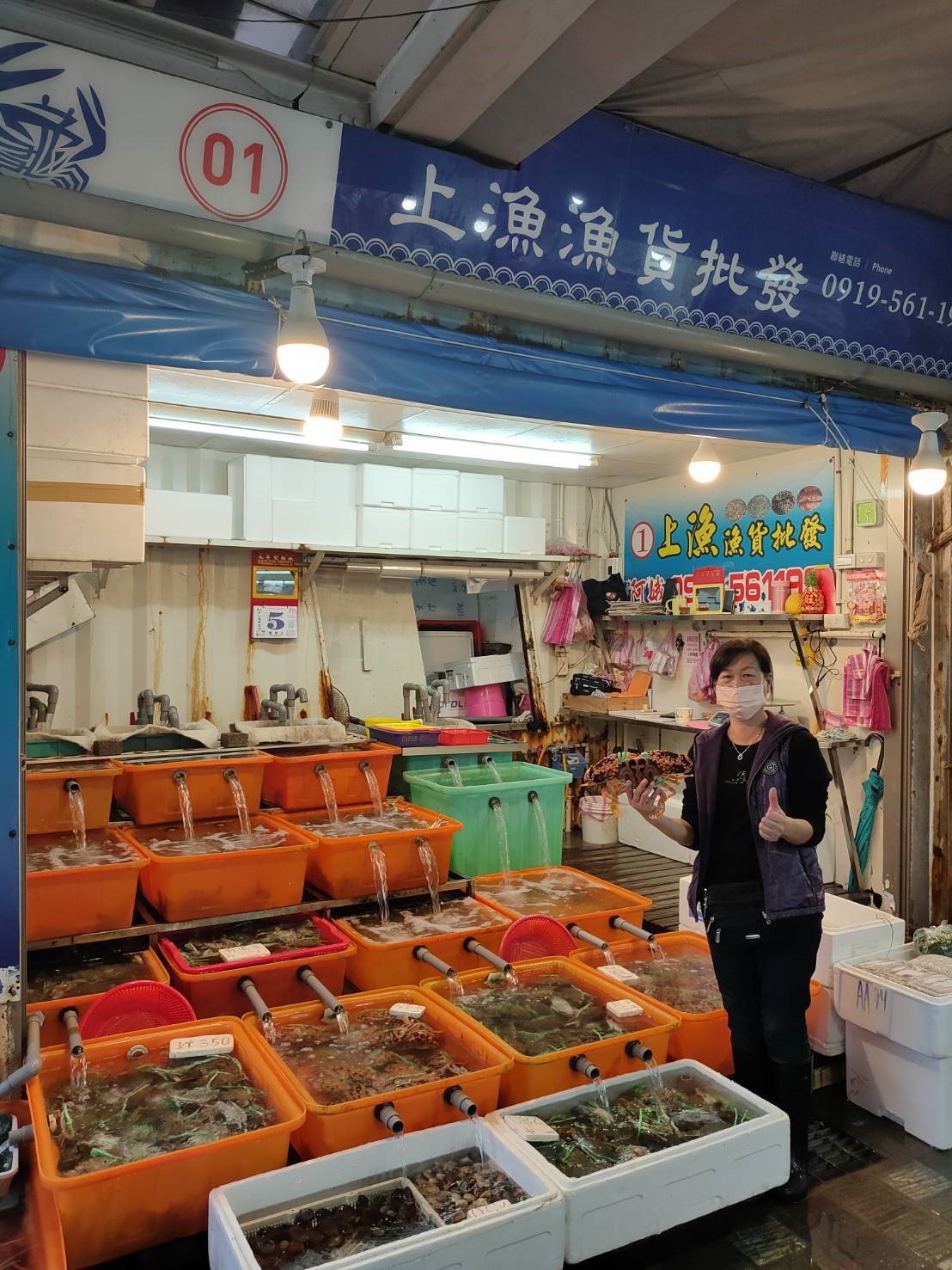 在龜吼漁夫市集經營生鮮攤位的陳女士，手持花蟹比讚。 圖：新北市漁業處提供