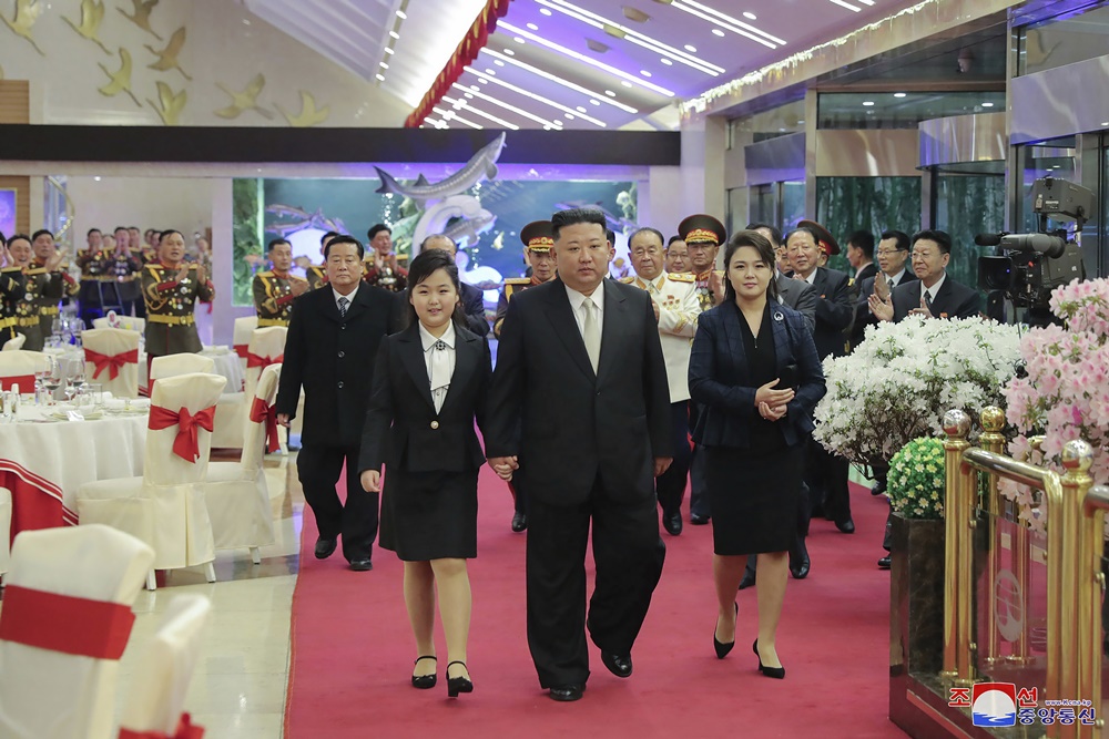 金正恩一家三口在兩側軍官的歡呼鼓掌下步入宴會現場。金朱愛梳了一顆在 80 年代稱得上時髦的「半屏山」髮型，身著一襲黑色套裝內搭白領襯衫，超齡的穿搭風格甚至不輸一旁 33 歲的母親李雪主。 圖：擷取自朝中社