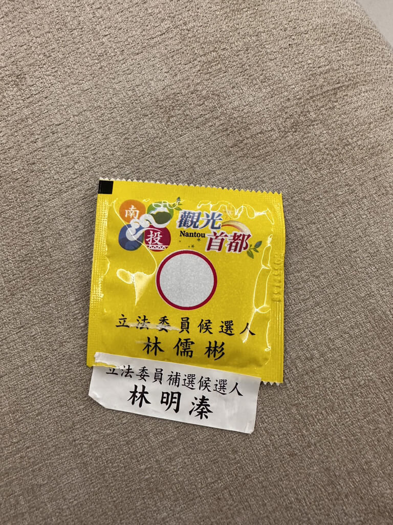 國民黨候選人林明溱的文宣品，撕開後卻是印著兒子林儒彬「立法委員候選人」的字樣。 圖：蔡培慧競辦提供