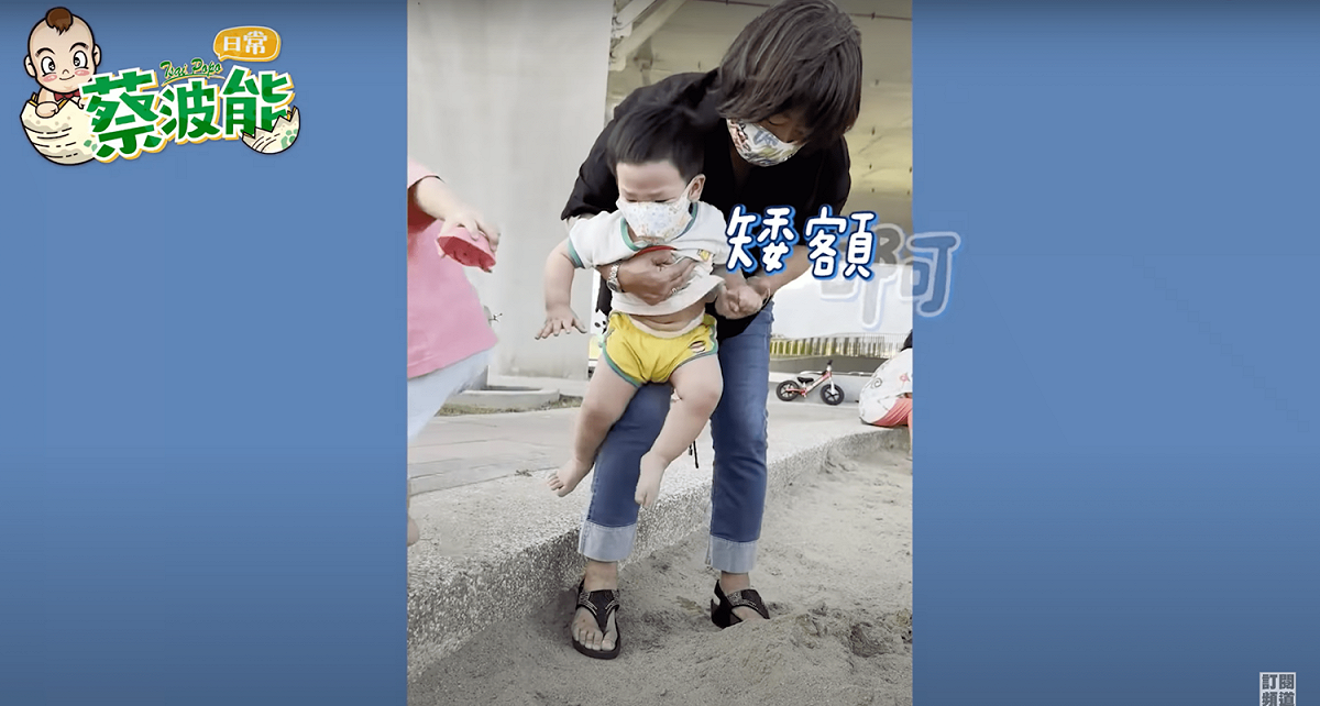 怕沙的波能需要阿嬤抱著進入沙池。 圖：取自Youtube：嘎嫂二伯&amp;蔡波能's Daily
